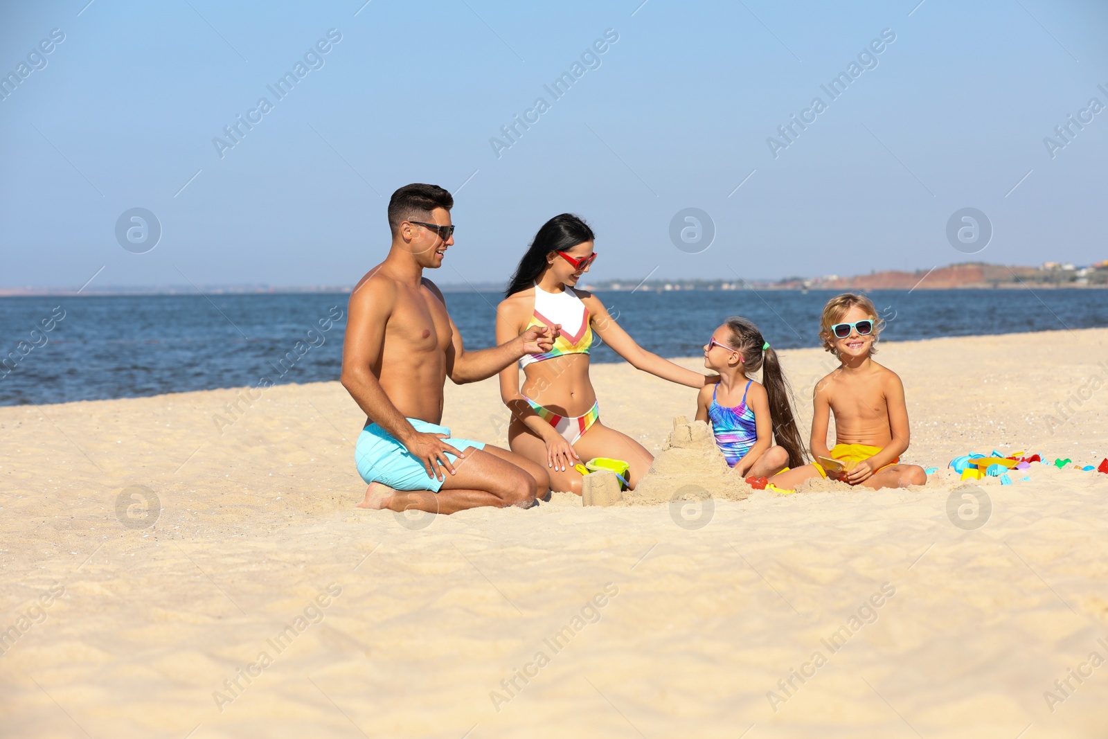 Photo of Happy family playing on sandy beach near sea. Summer holidays