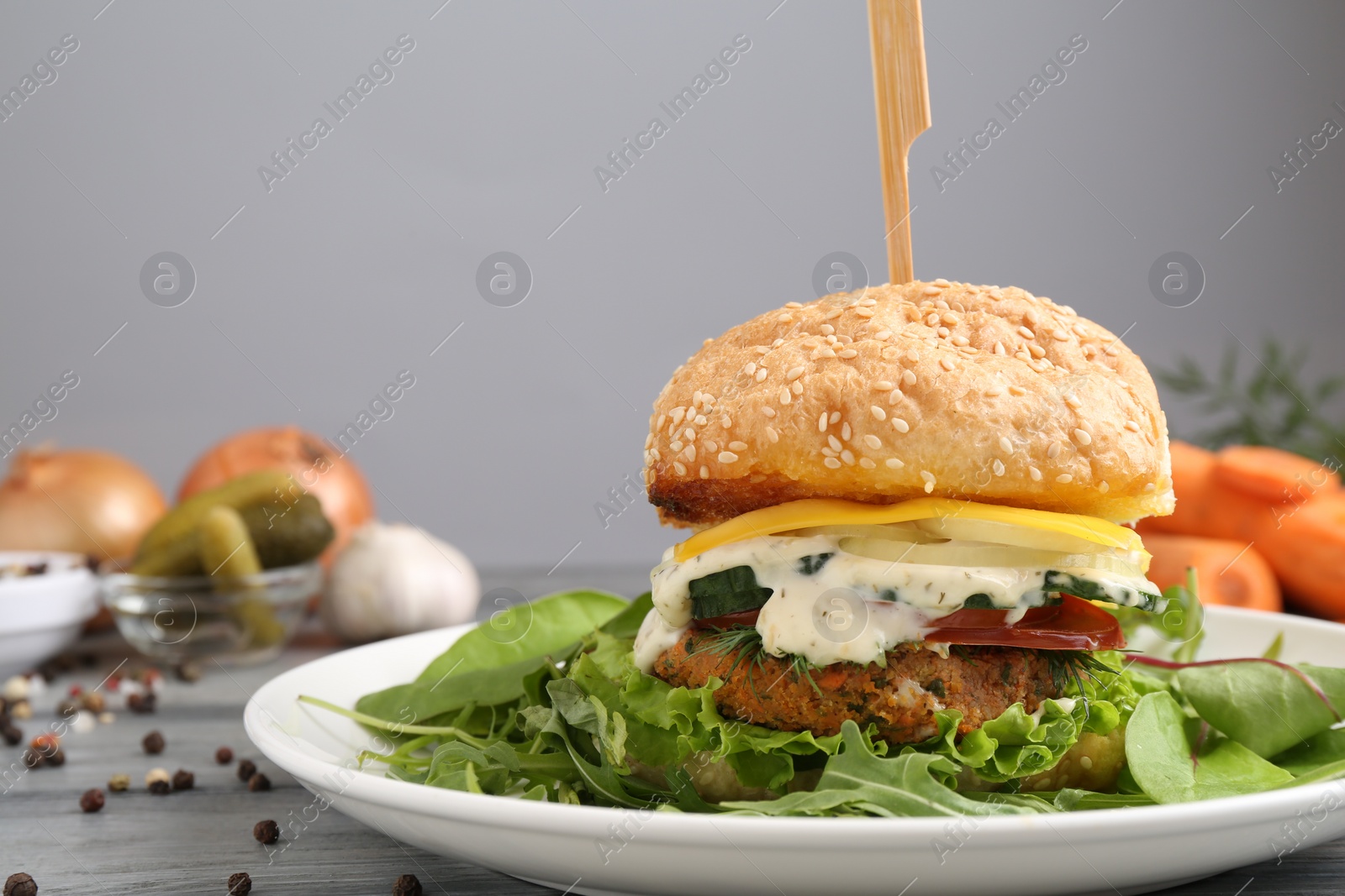 Photo of Delicious vegetarian burger served on grey wooden table