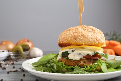 Photo of Delicious vegetarian burger served on grey wooden table