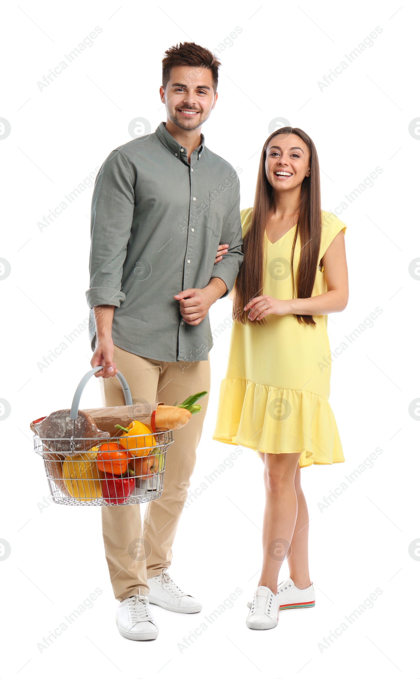 Photo of Young couple with shopping basket full of products isolated on white