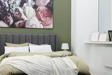 Photo of Comfortable bed and painting on wall in bedroom. Stylish interior design