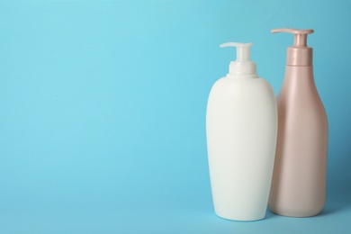 Photo of Bottles with hair care cosmetics on light blue background