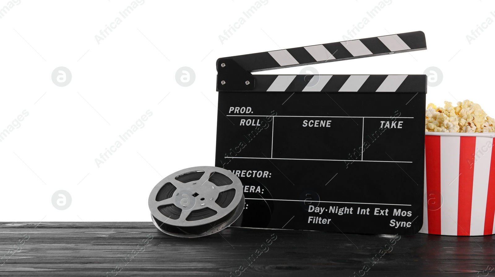 Photo of Movie clapper, bucket of tasty popcorn and film reel on wooden table against white background, space for text