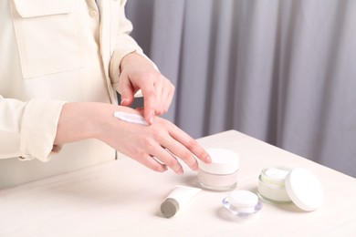 Woman applying hand cream at home, closeup