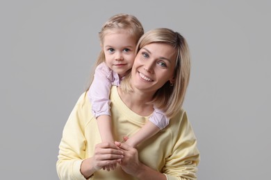 Family portrait of happy mother and daughter on grey background