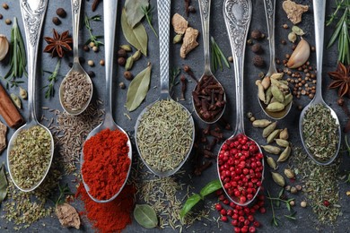Flat lay composition with different natural spices and herbs on black table