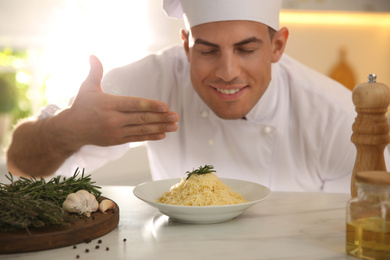 Photo of Professional chef cooking at table in kitchen, focus on dish