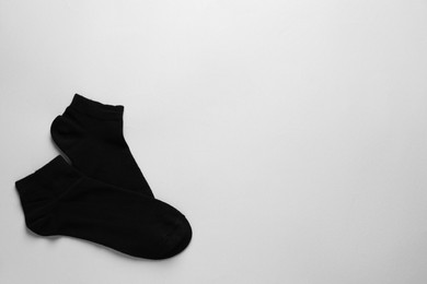 Pair of black socks on light grey background, flat lay. Space for text