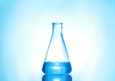 Photo of Laboratory flask with liquid on color background. Solution chemistry