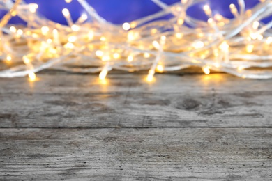 Photo of Wooden table and blurred Christmas lights on background