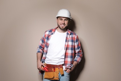 Photo of Young working man in hardhat standing on color background