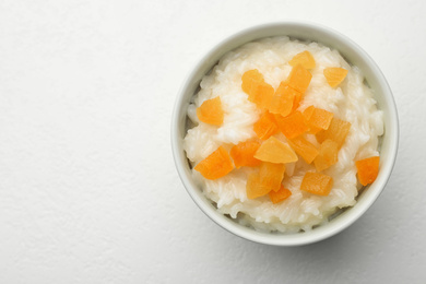 Photo of Delicious rice pudding with dried apricots on white table, top view. Space for text