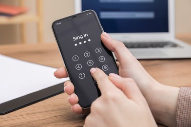 Photo of Woman unlocking smartphone with blocked screen at wooden table, closeup