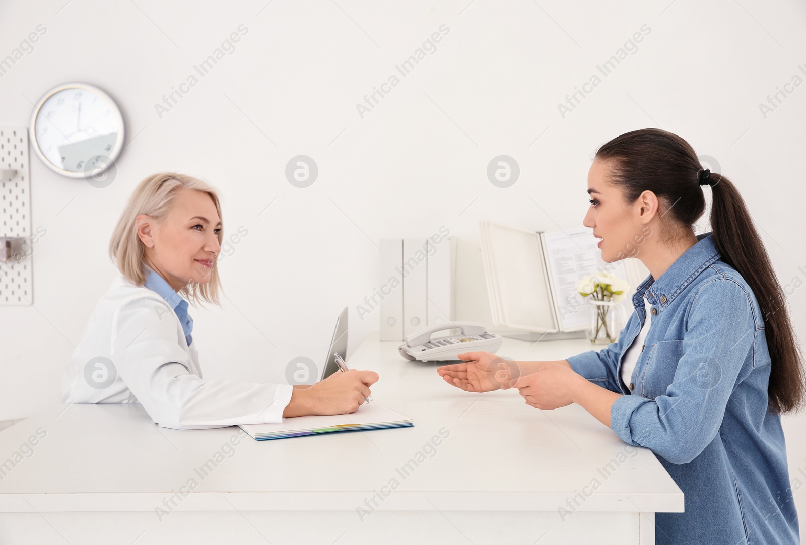 Photo of Senior female receptionist working with client in hospital