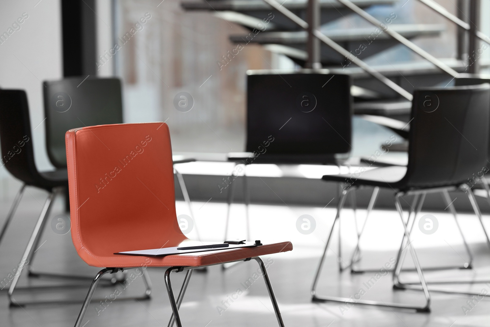 Photo of Red chair with clipboard in office prepared for group therapy. Meeting room interior