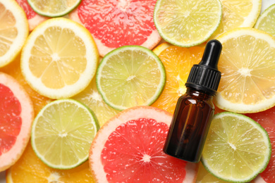 Photo of Bottle of essential oil on pile of citrus slices, flat lay. Space for text