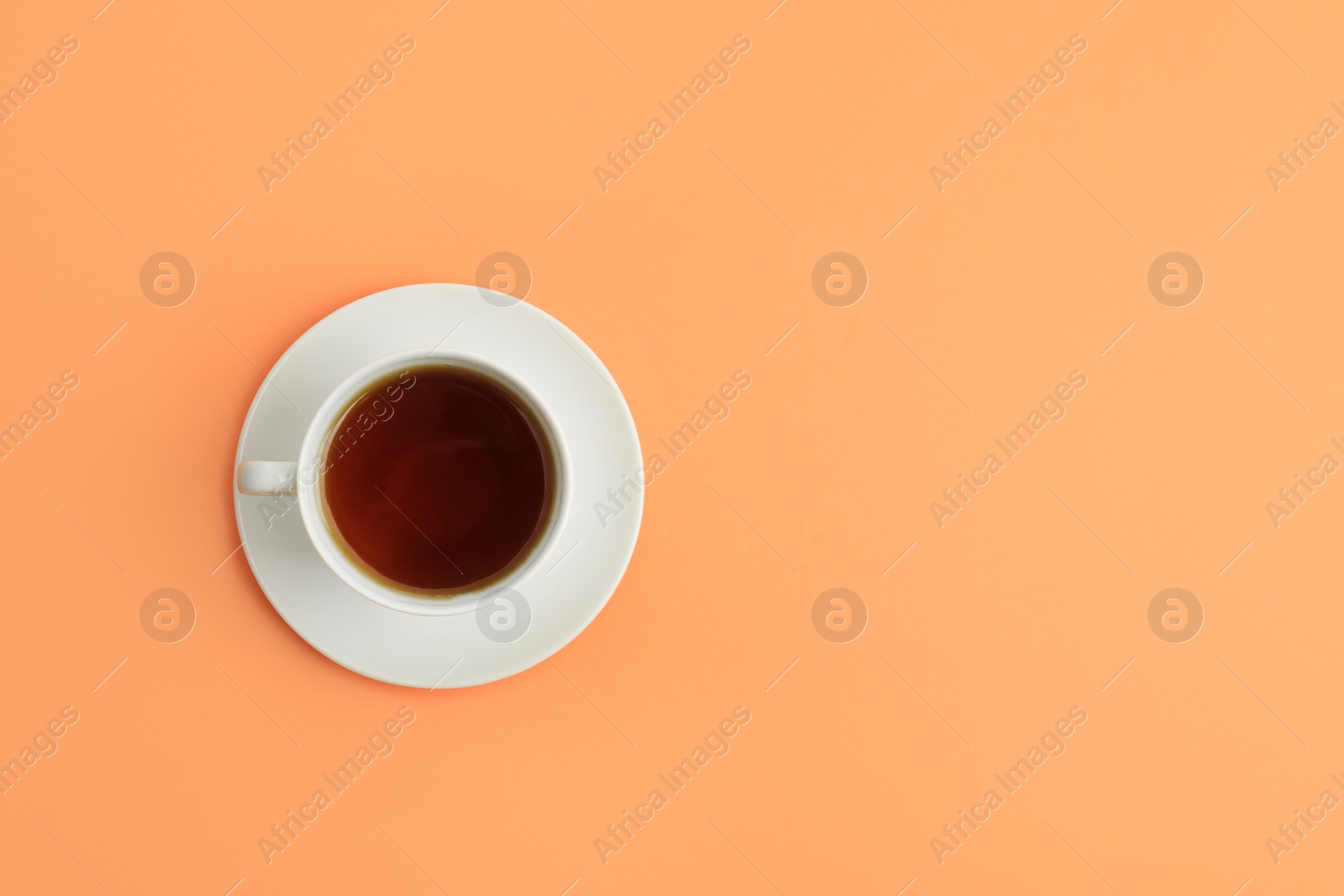 Photo of Cup of tea on coral background, top view. Space for text