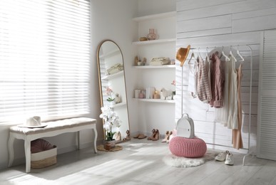 Rack with different stylish clothes, shoes and decorative elements in dressing room. Interior design