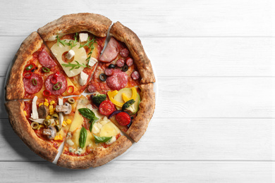 Photo of Slices of different delicious pizzas on white wooden table, top view. Space for text