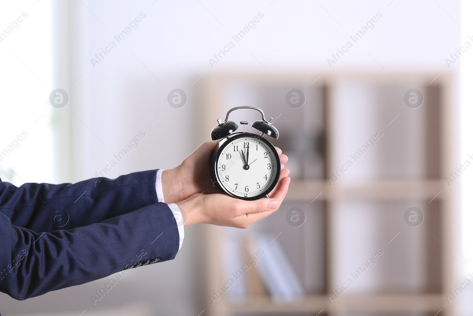 Photo of Businesswoman holding alarm clock on blurred background. Time concept