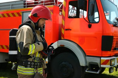 Photo of Firefighter in uniform near fire truck outdoors