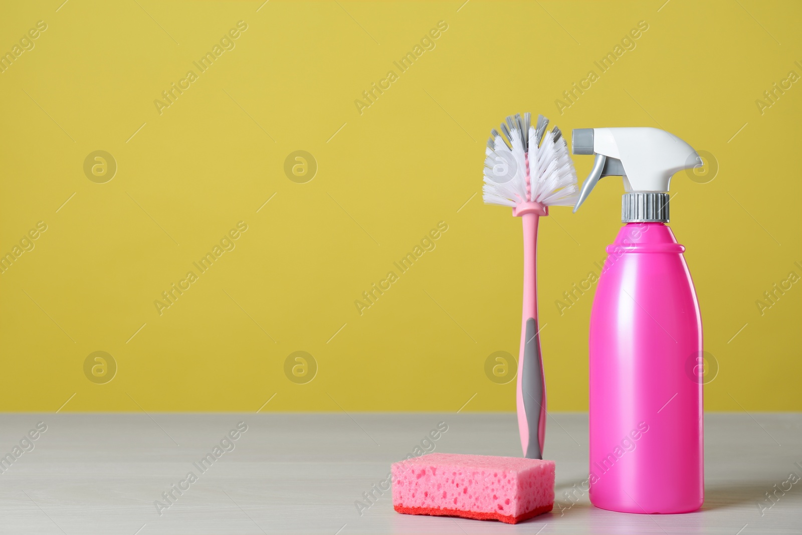 Photo of Bottle of cleaning product and supplies on light table. Space for text