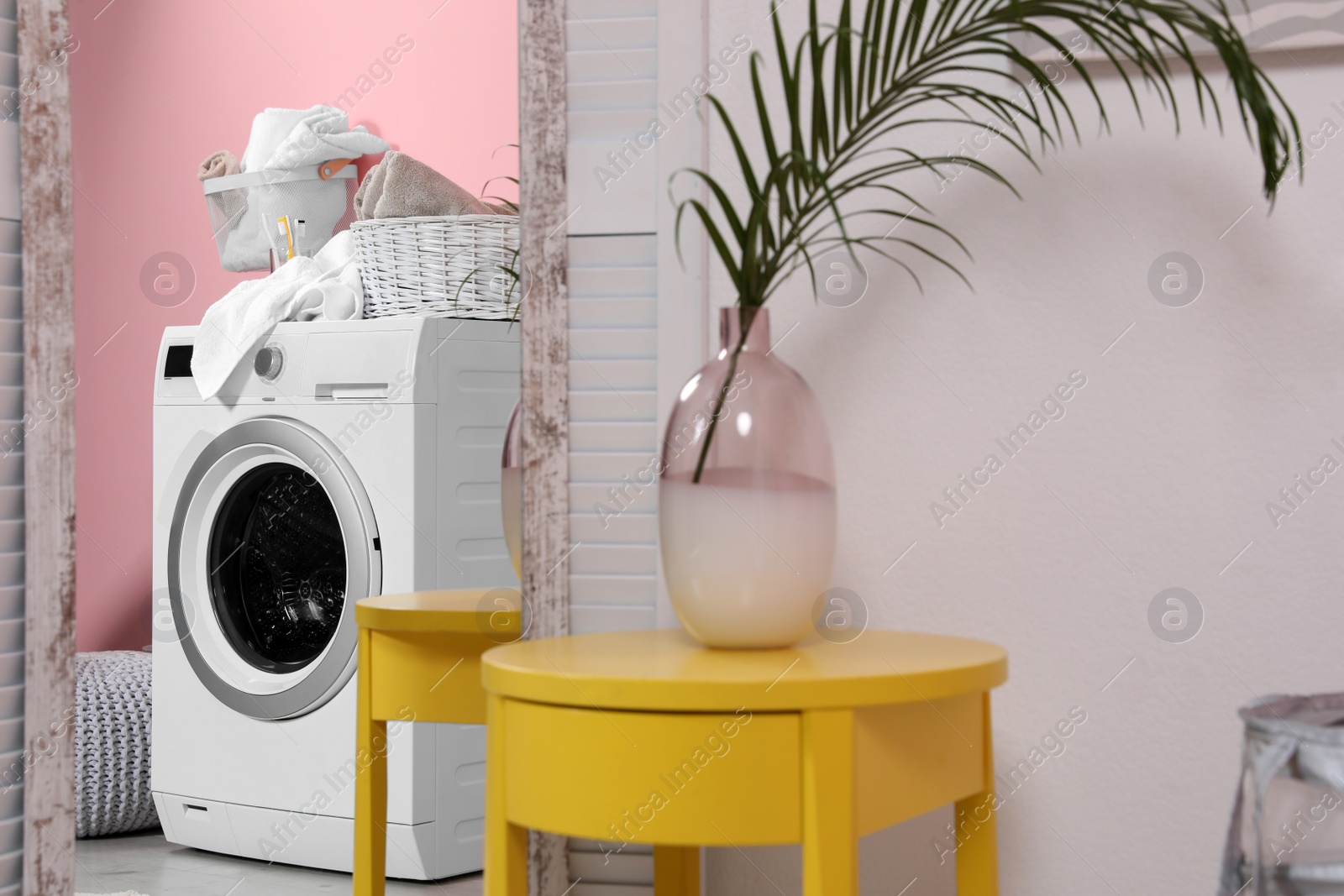 Photo of Reflection of modern washing machine in mirror at home. Laundry room