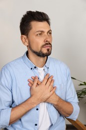 Man with clasped hands praying in room at home