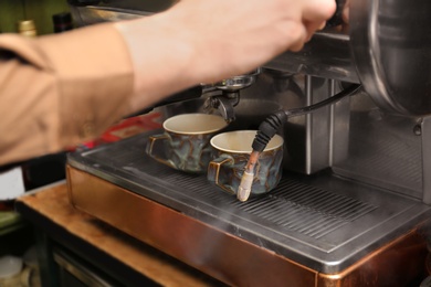 Photo of Barista preparing espresso using coffee machine, closeup