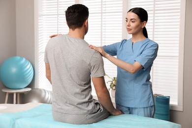 Photo of Orthopedist examining man in clinic. Scoliosis treatment