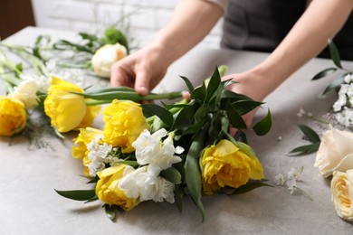 Florist making beautiful bouquet at grey table, closeup