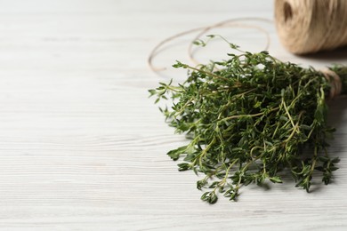 Bunch of aromatic thyme on white wooden table, closeup. Space for text