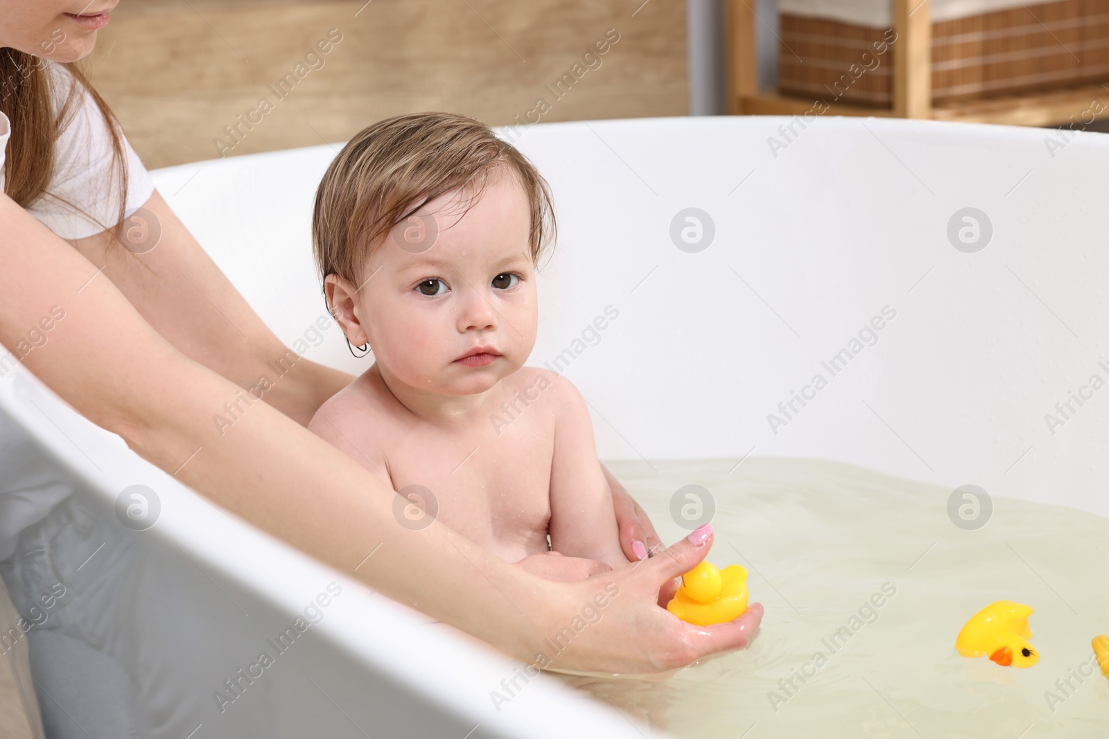 Photo of Mother bathing her cute little baby in tub at home