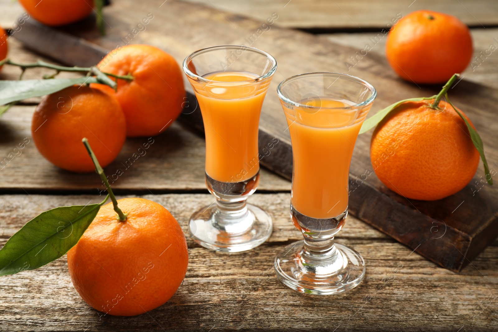 Photo of Delicious tangerine liqueur and fresh fruits on wooden table