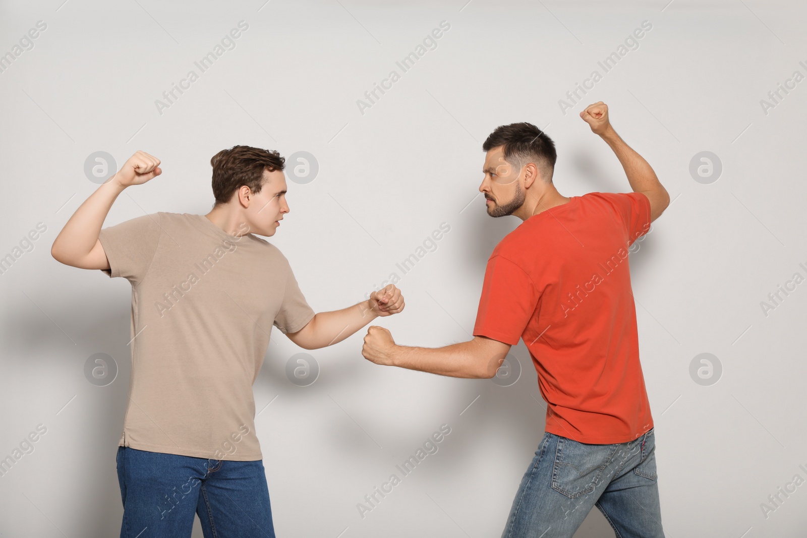 Photo of Two emotional men fighting on beige background