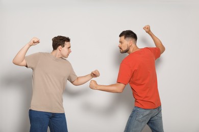 Two emotional men fighting on beige background