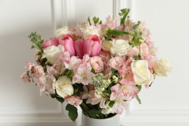 Photo of Beautiful bouquet of fresh flowers in vase near white wall