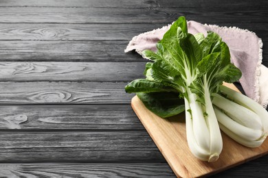 Photo of Fresh green bok choy cabbages on black wooden table. Space for text