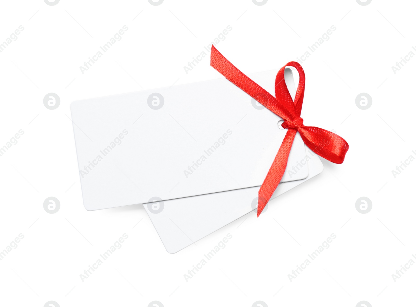 Photo of Blank gift tags with red satin ribbon on white background. Space for design