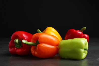 Photo of Fresh ripe bell peppers on table against black background