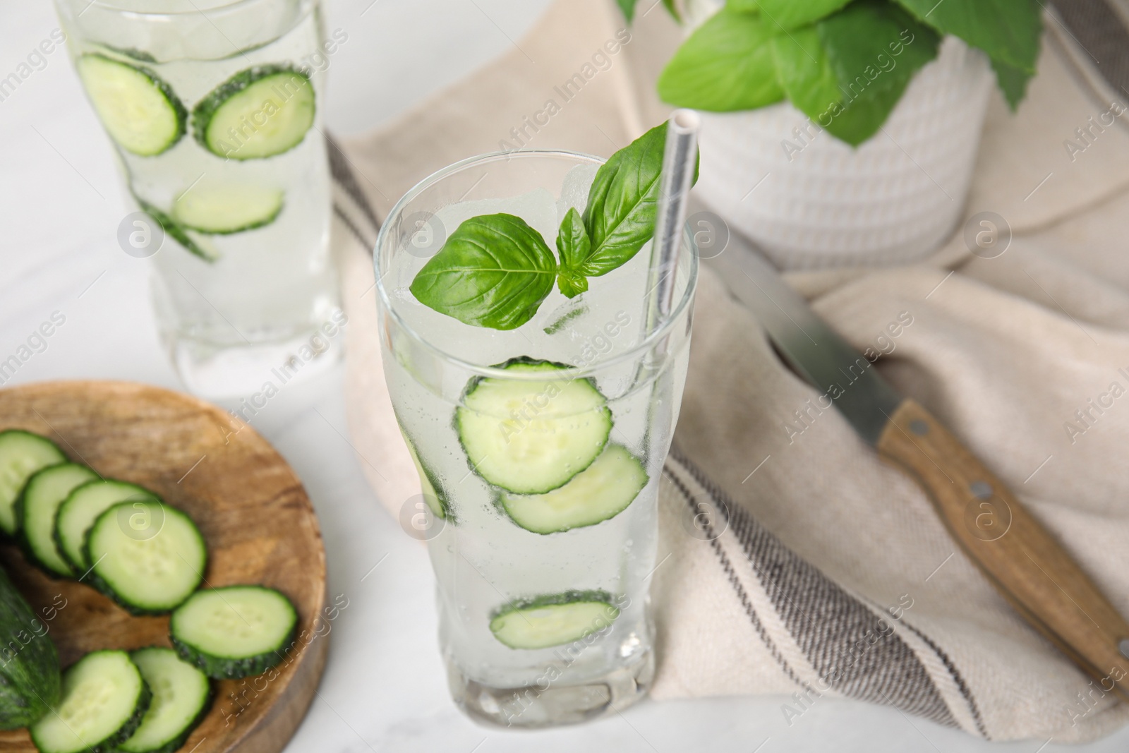 Photo of Tasty fresh cucumber water with basil on white table