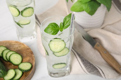 Photo of Tasty fresh cucumber water with basil on white table