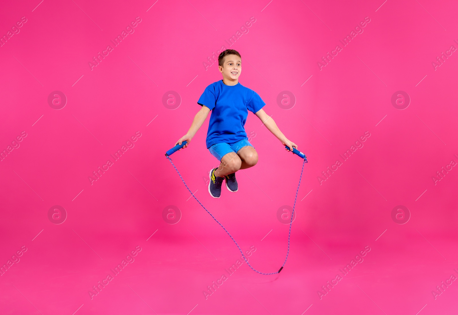 Photo of Full length portrait of boy jumping rope on color background