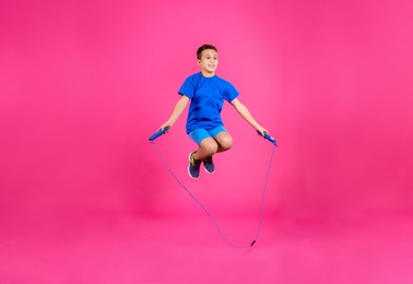 Photo of Full length portrait of boy jumping rope on color background