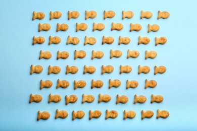 Photo of Delicious goldfish crackers on light blue background, flat lay