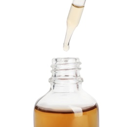 Essential oil dripping from pipette into glass bottle on white background