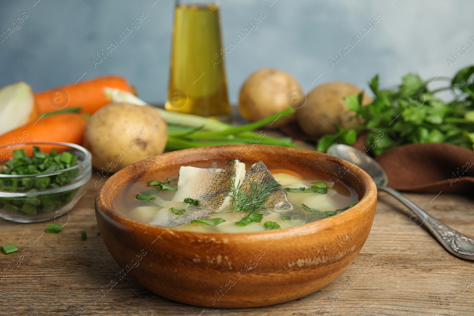 Photo of Delicious fish soup in bowl on wooden table