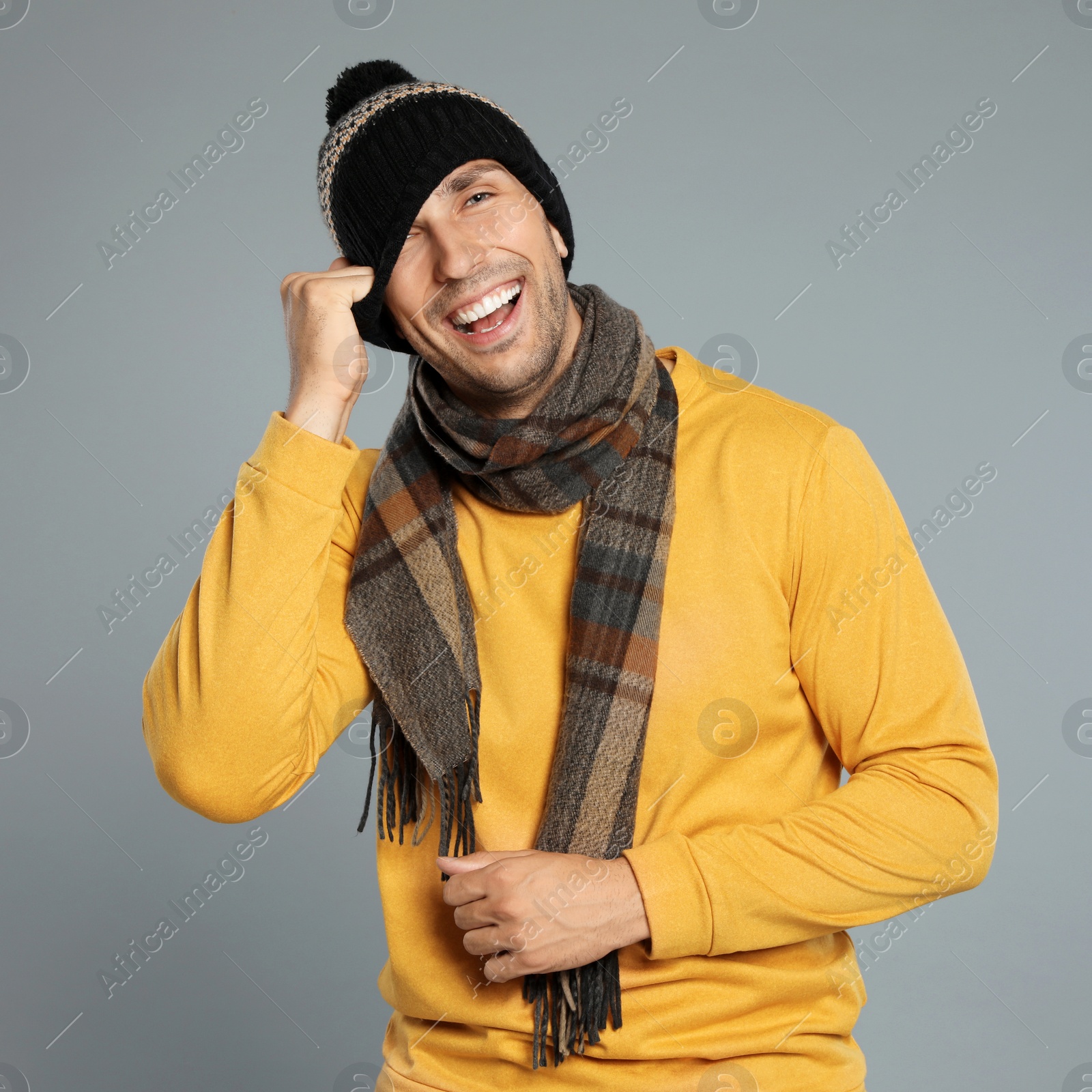 Photo of Happy young man in warm clothes on grey background. Winter season