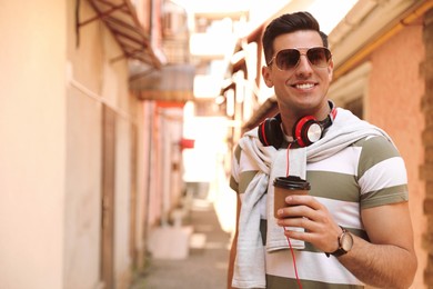 Photo of Happy man with coffee on city street in morning