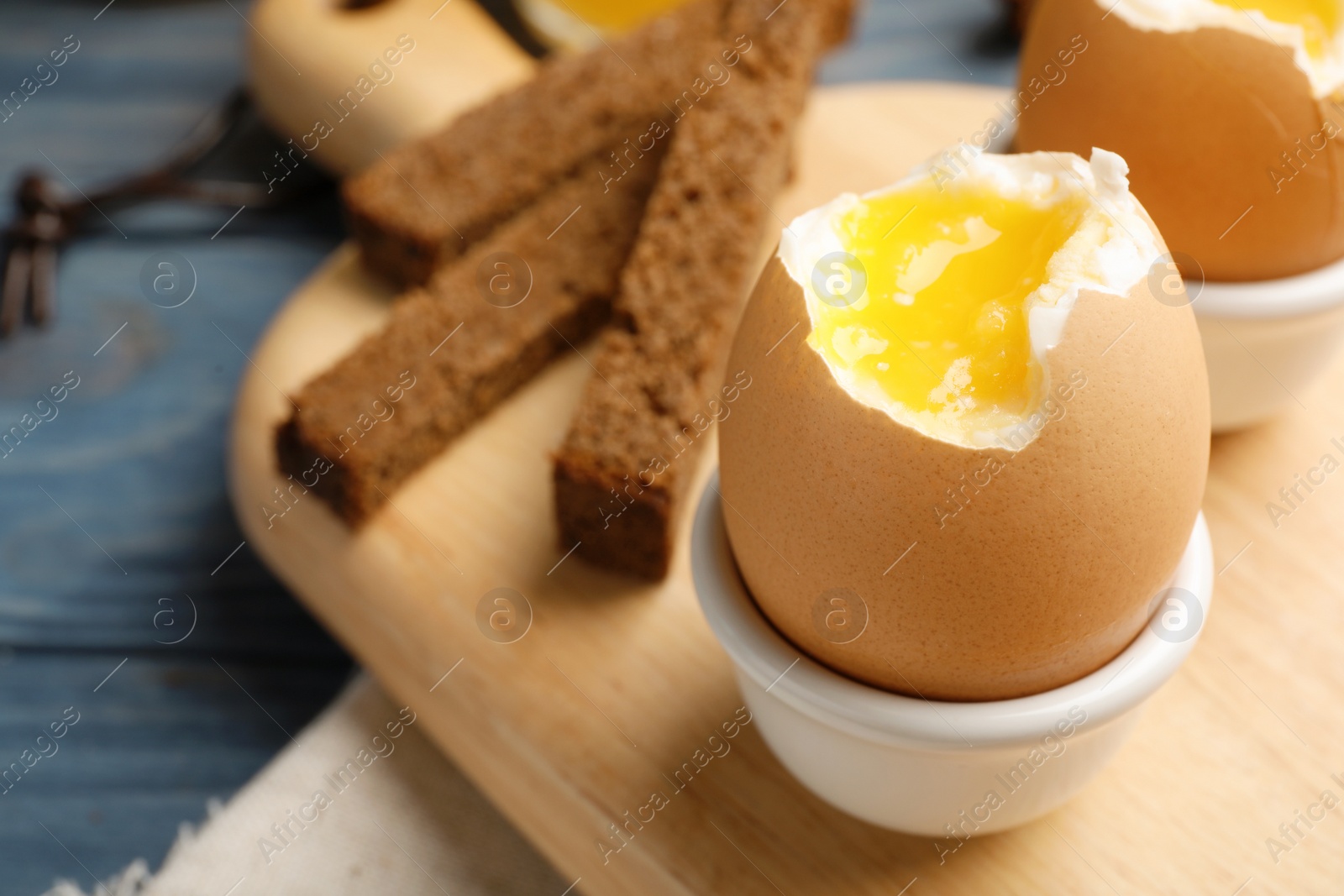 Photo of Holder with soft boiled egg on table. Space for text